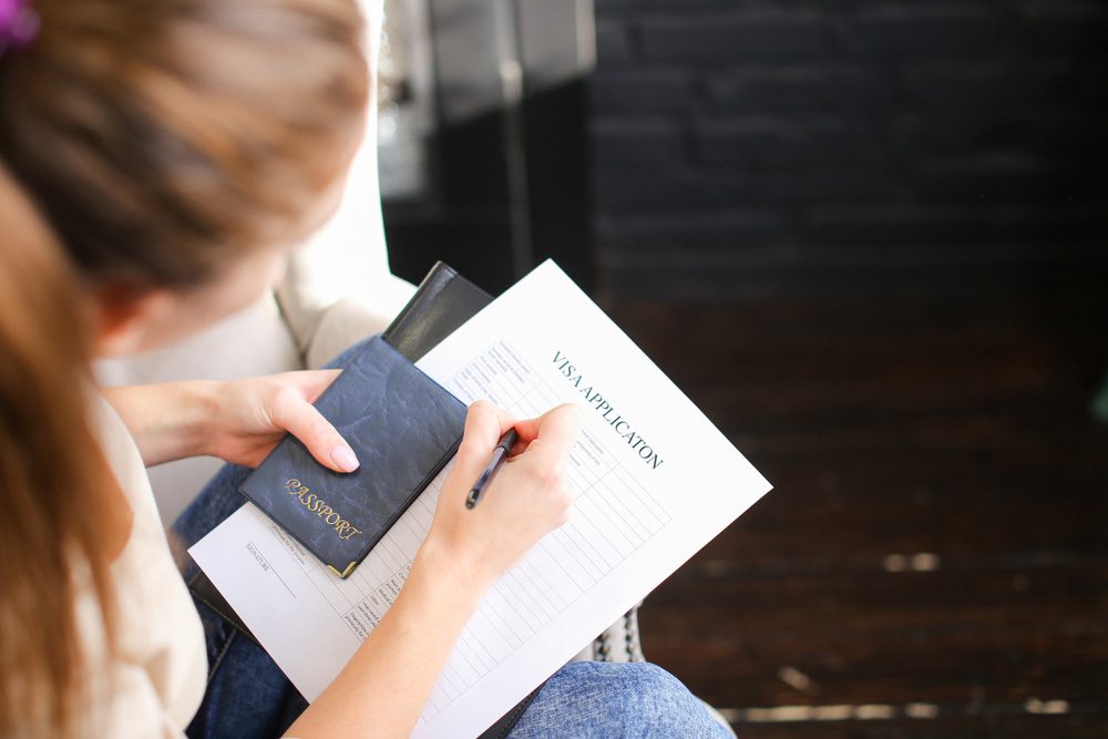 Woman completing a Visa Application Form - candid photograph - Citizenship by Investment - PassPro banner Image